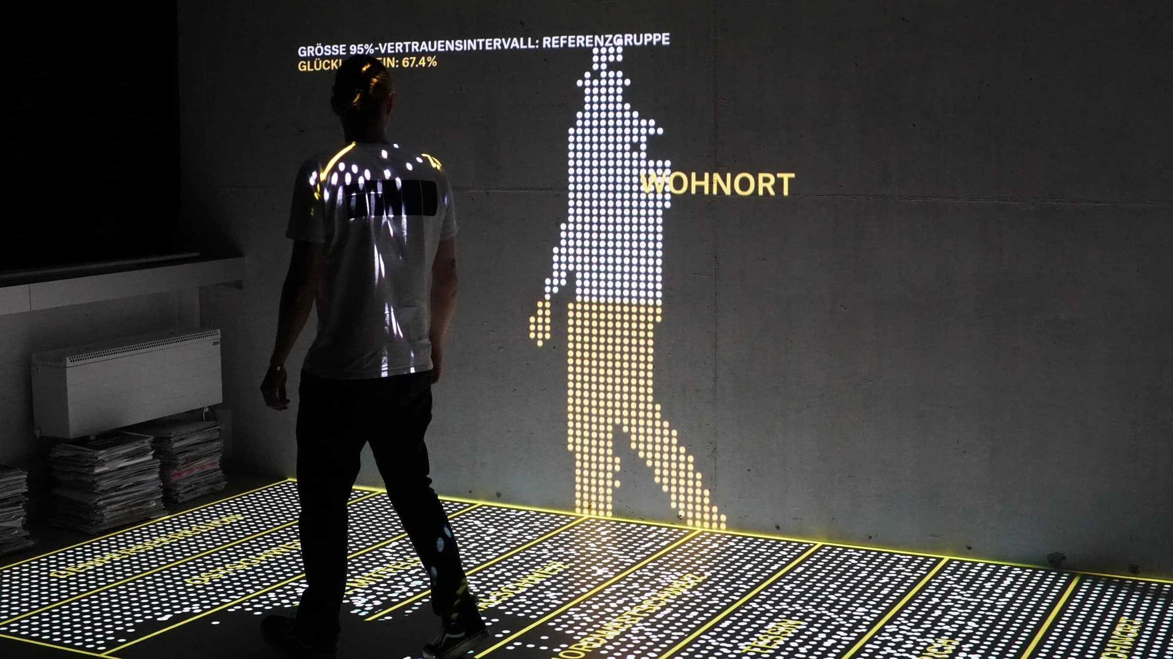 Person walking beside a dot-matrix figure projected on the floor and wall
