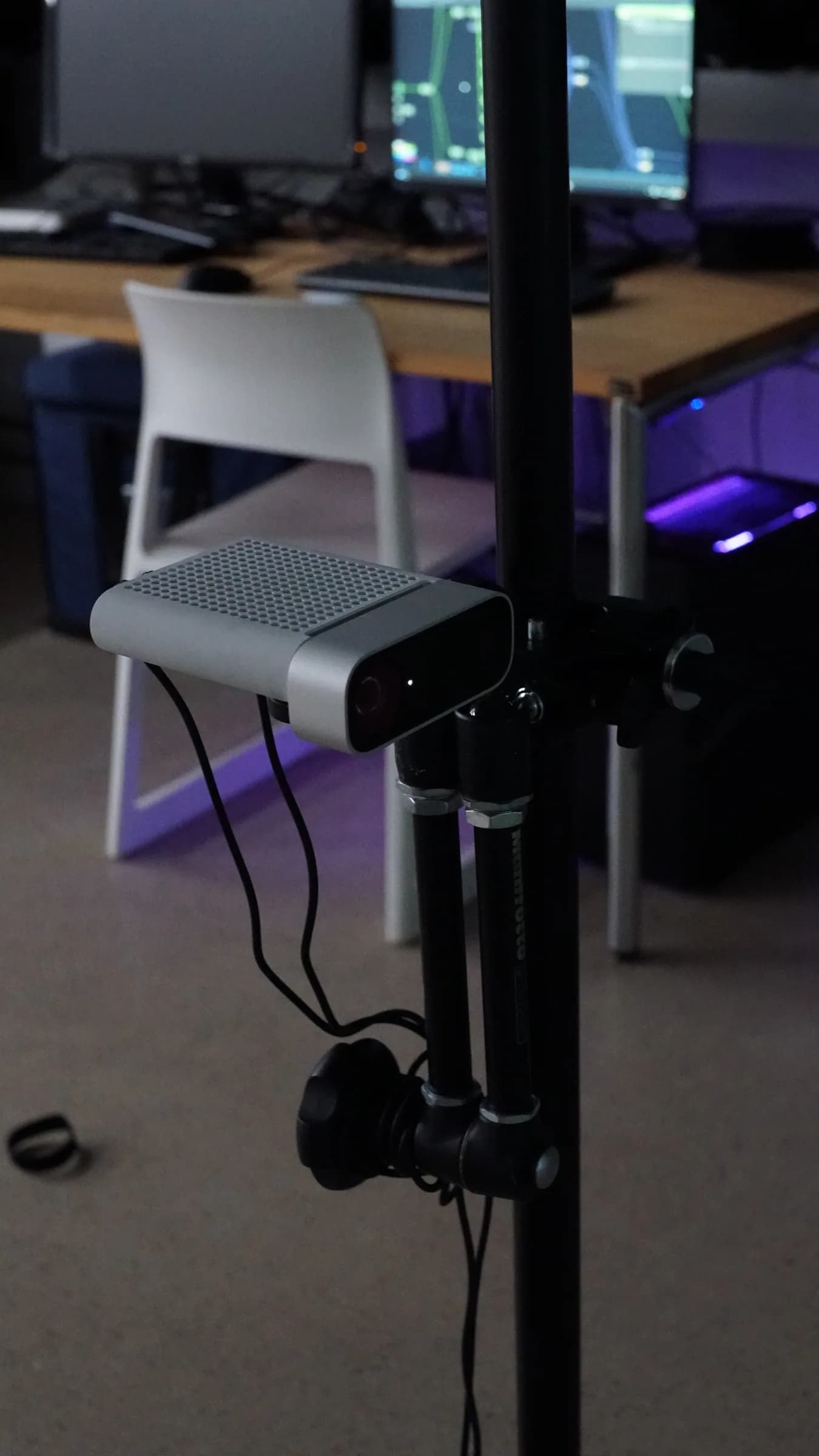 Depth camera mounted on a tripod in front of a workstation