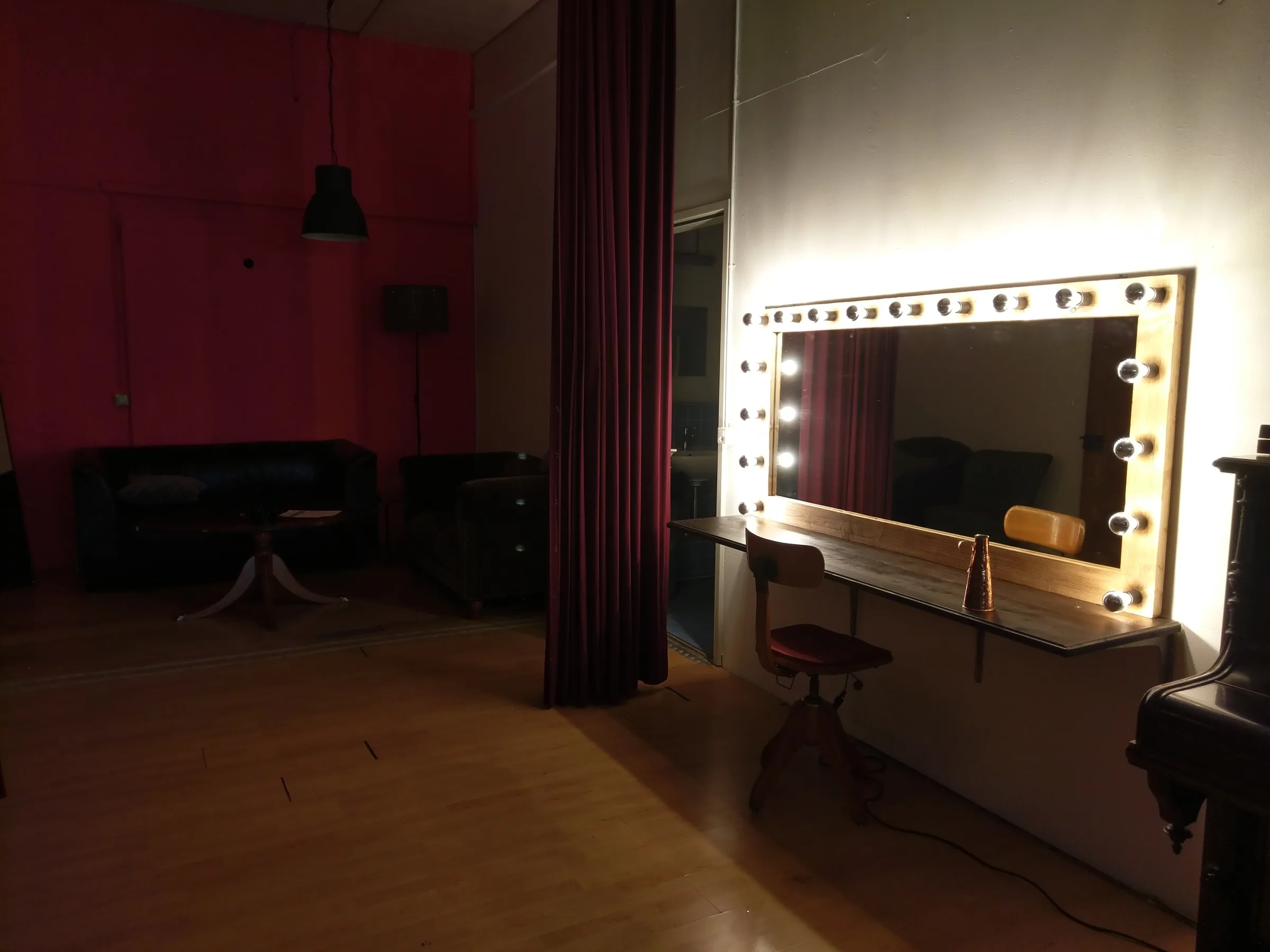 Dressing room with a bulb-framed mirror and red curtains