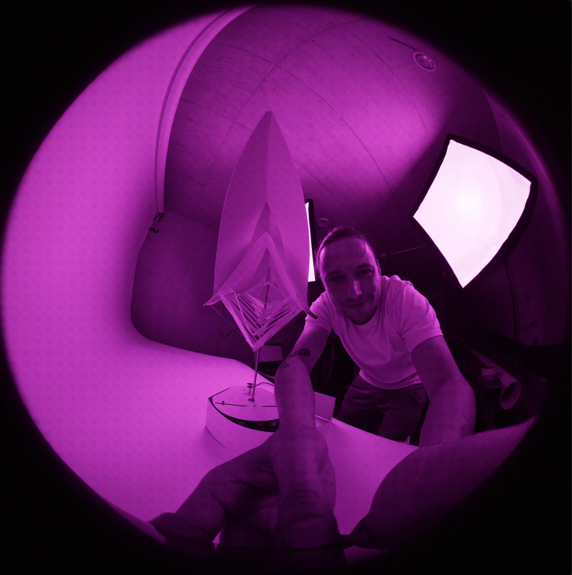Fisheye photograph inside a purple-lit installation with a pyramid-shaped object