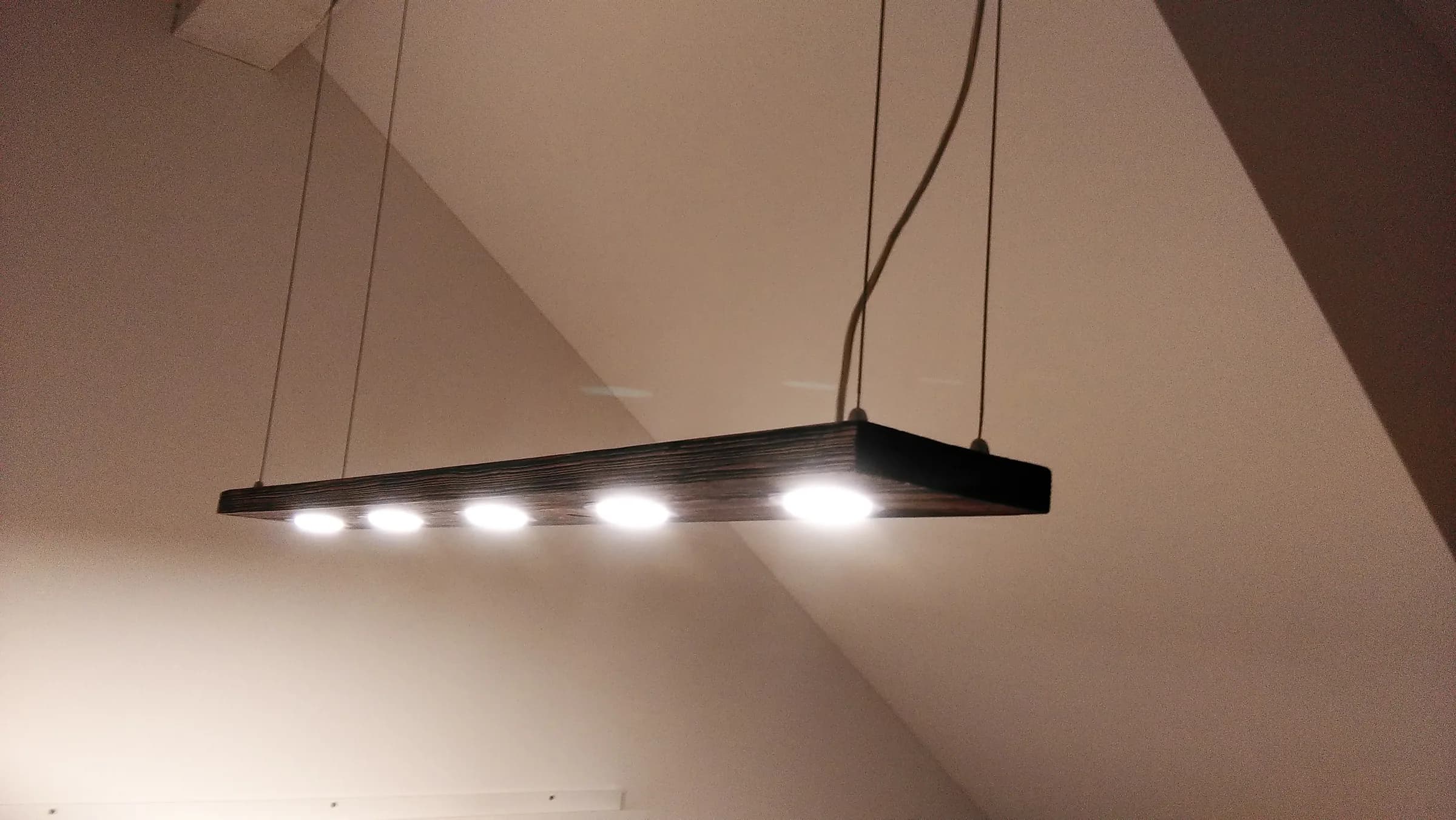 Dark wooden bar pendant with five LED spots hanging under a sloped ceiling