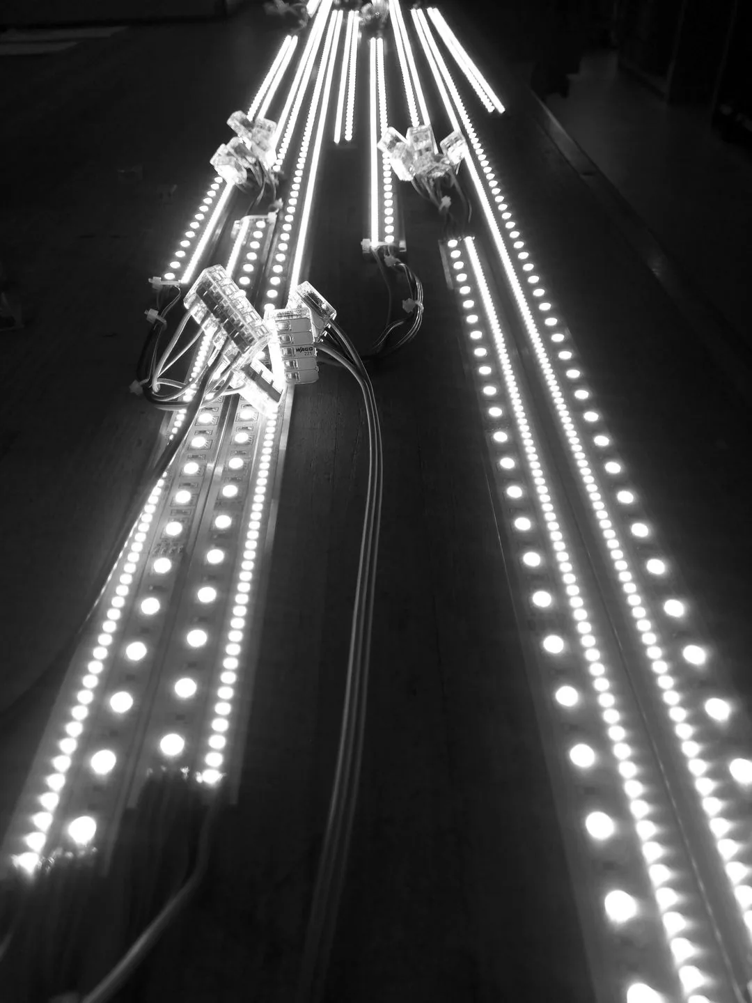 Black-and-white photograph of long LED strips running across the floor