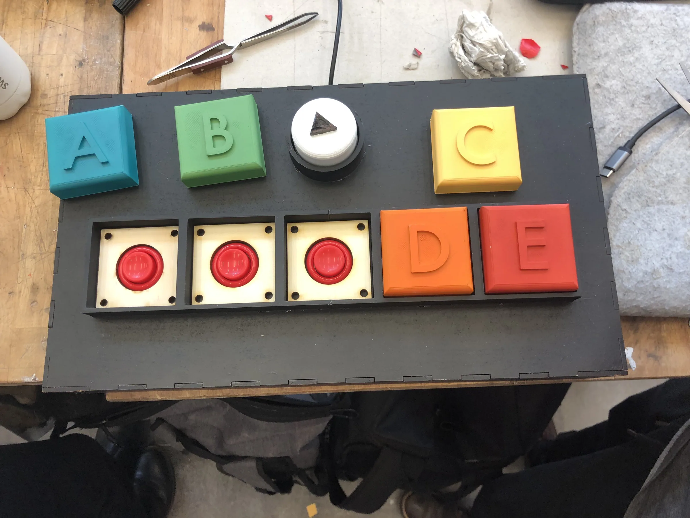Handmade controller with coloured letter blocks A to E and red arcade buttons on a dark board