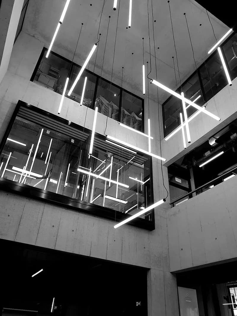 Light installation: black-and-white view up a building atrium with white line lights suspended at angles