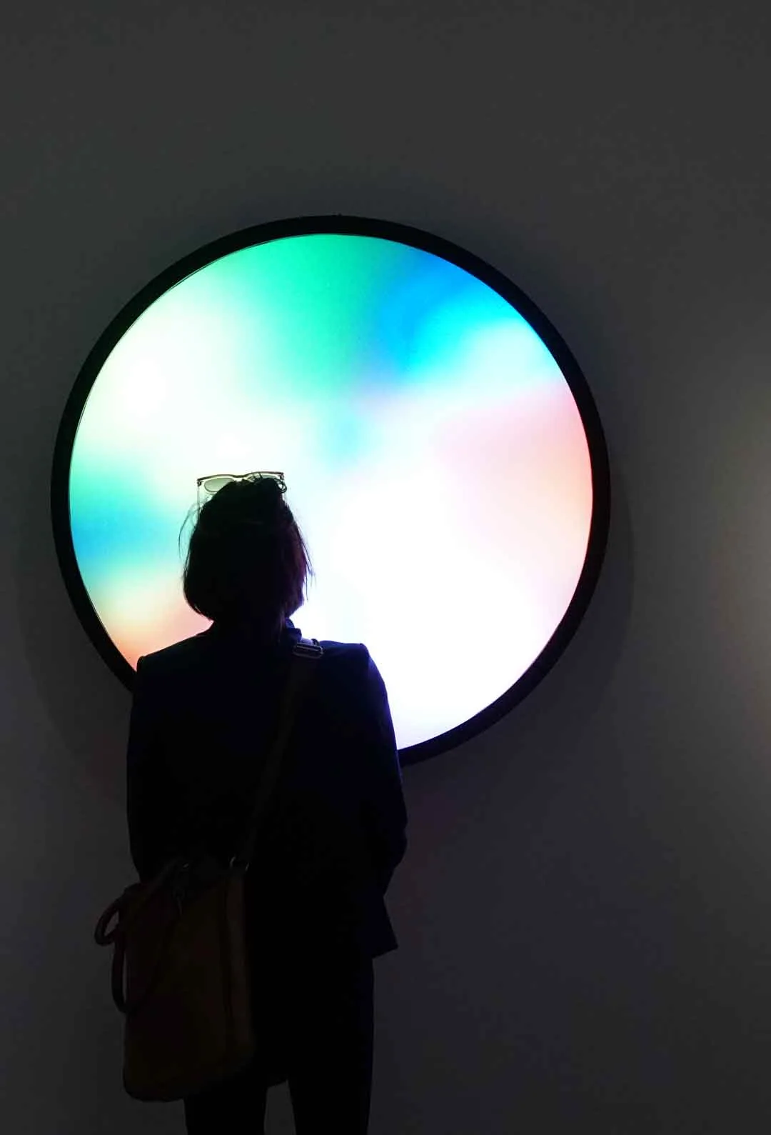 Visitor standing in front of a round glowing colour-gradient light