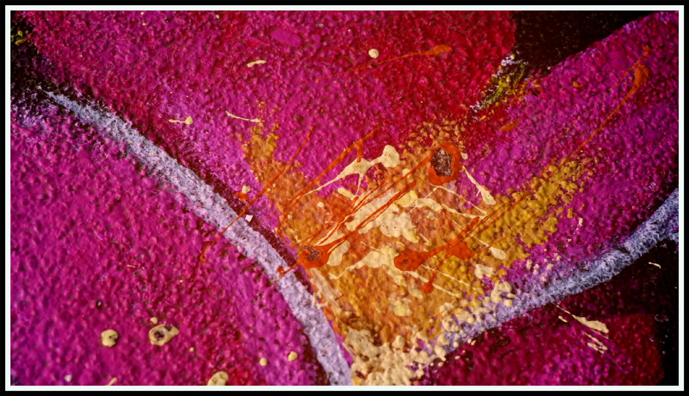 Close-up of a pink textured surface with orange paint marks and a lavender seam