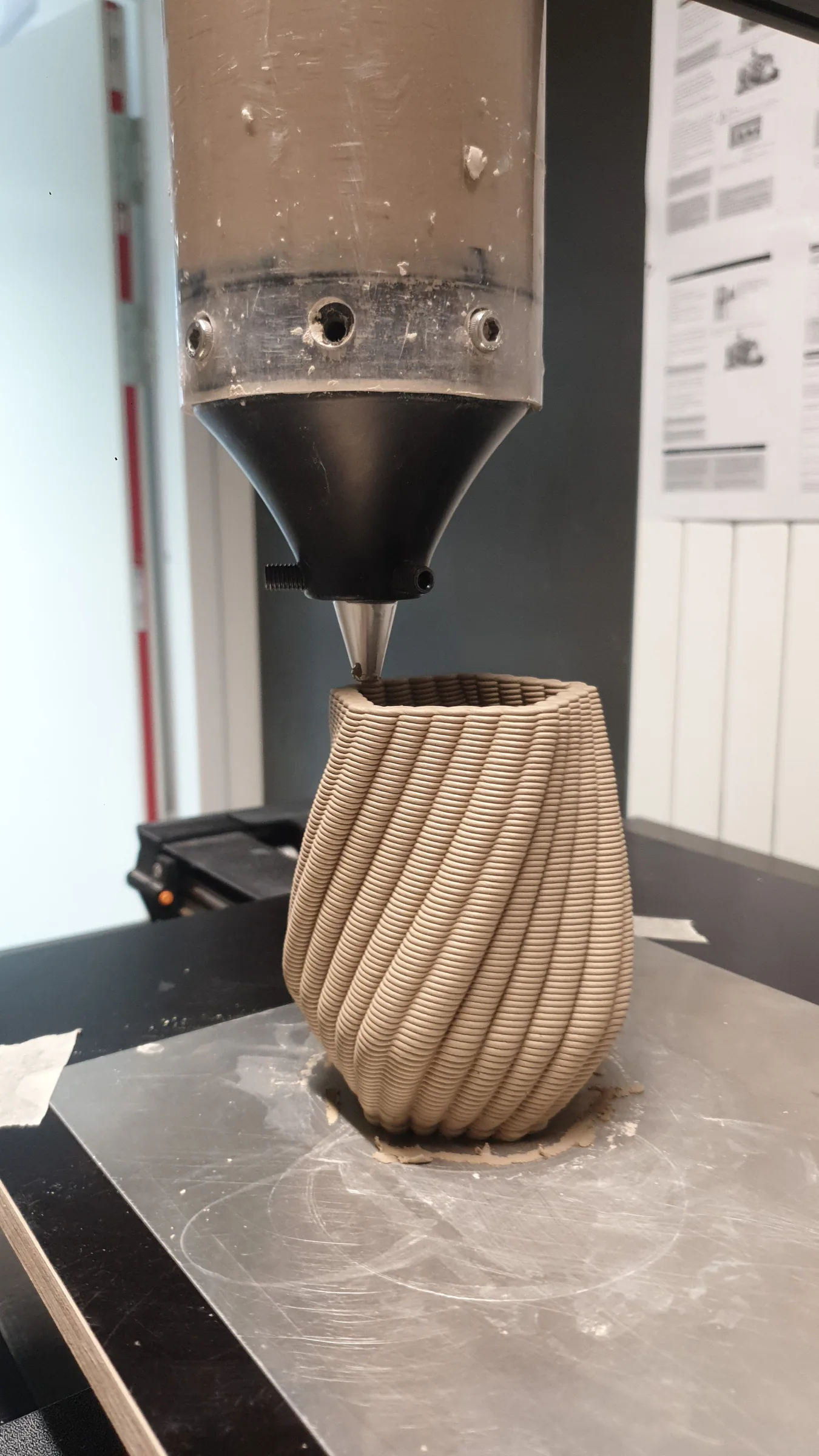 3D printer extruding a spiral-ribbed clay vase