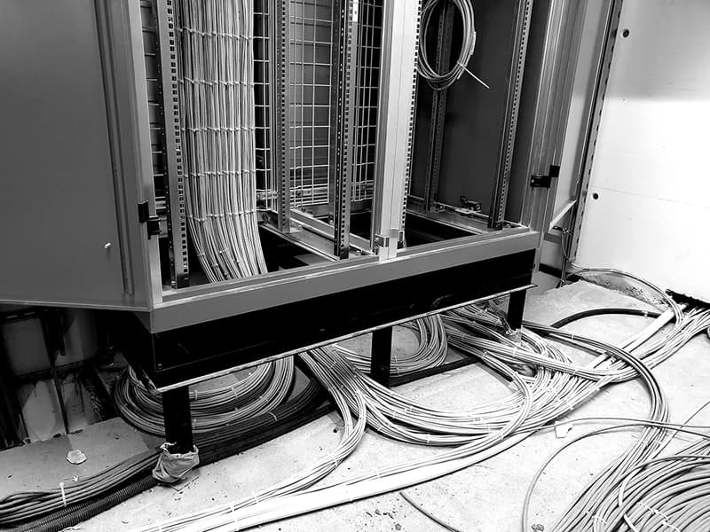 Black-and-white photograph of cables spilling from an open server cabinet